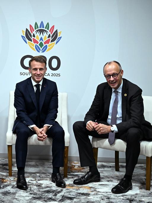 Der britische Premierminister Keir Starmer (links), Frankreichs Präsident Emmanuel Macron (Mitte) und Bundeskanzler Friedrich Merz lächeln für die Kameras beim G20-Gipfel in Johannesburg