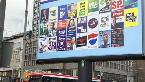 Verschiedene Wahlplakate auf einem großen Screen in einer Innenstadt