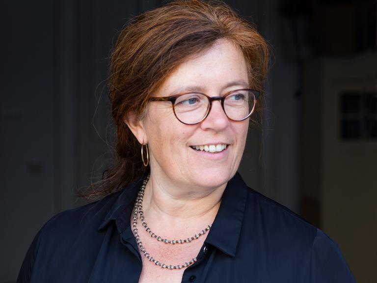 Porträt der Rechtsanwältin Christina Clemm. Sie hat lange rote Haare und trägt eine Brille.