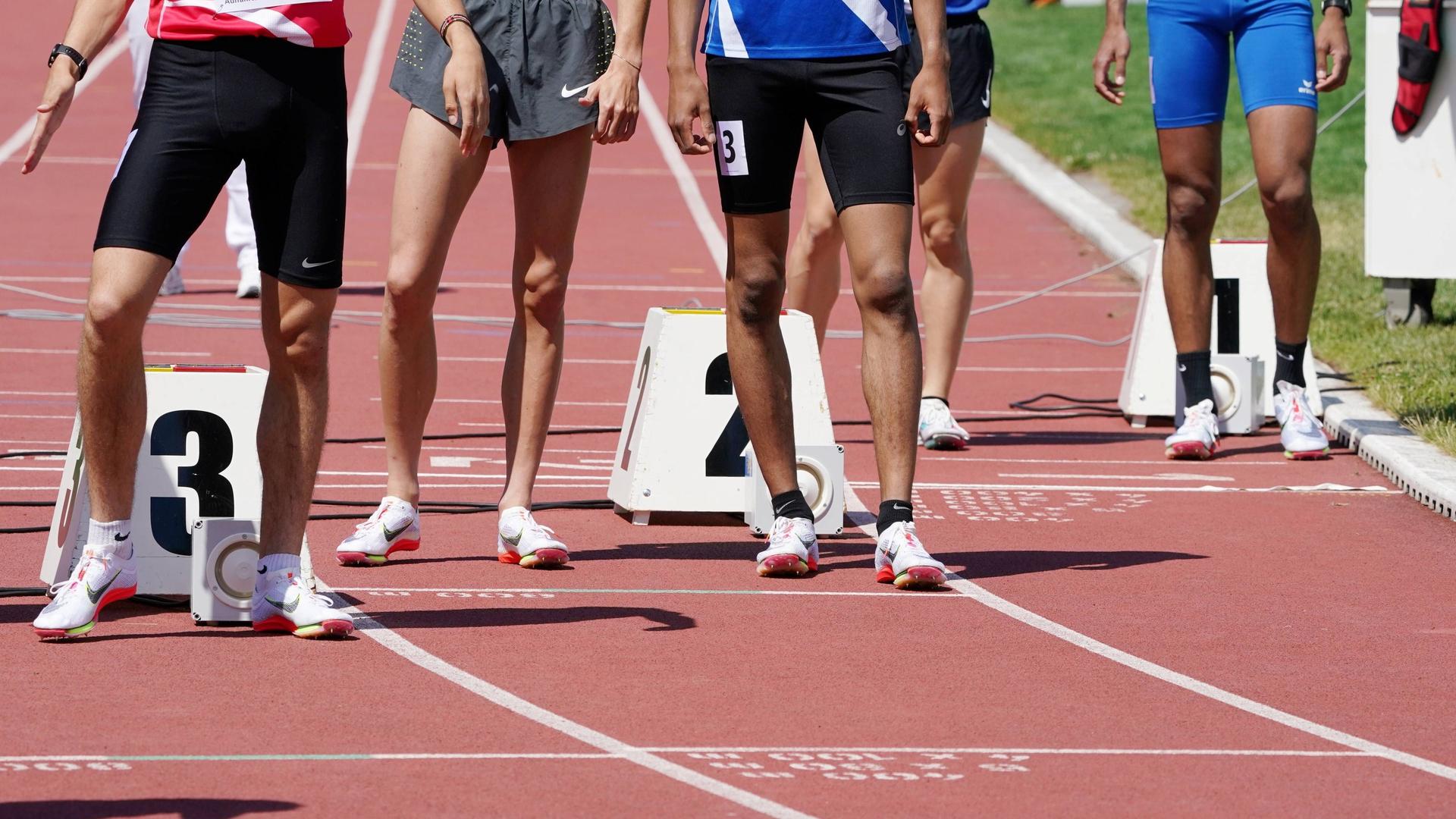 Detailaufnahme der Beine der Läufer vor dem Start bei einem Leichtathletik-Event in der Schweiz.