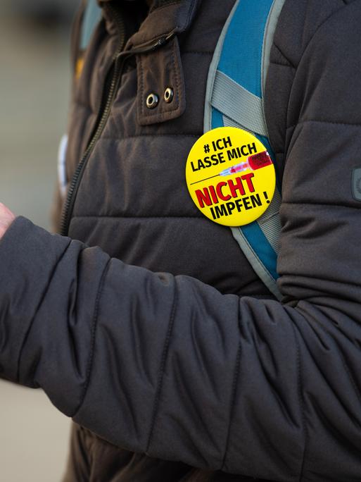 "Querdenker" Anti-Lockdown Protest in Leipzig. Ein Demonstrant trägt den Button: "#ich lasse mich nicht impfen" am Rucksack und tippt in sein Smartphone, 06.11.2021.