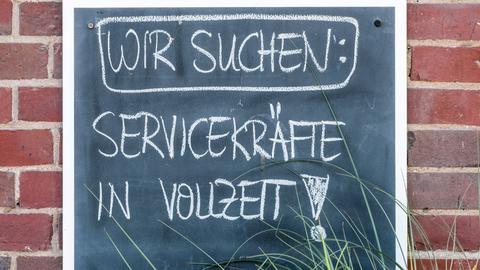 Auf einem Schild steht mit Kreide geschrieben: Wir suchen Servicekräfte in Vollzeit