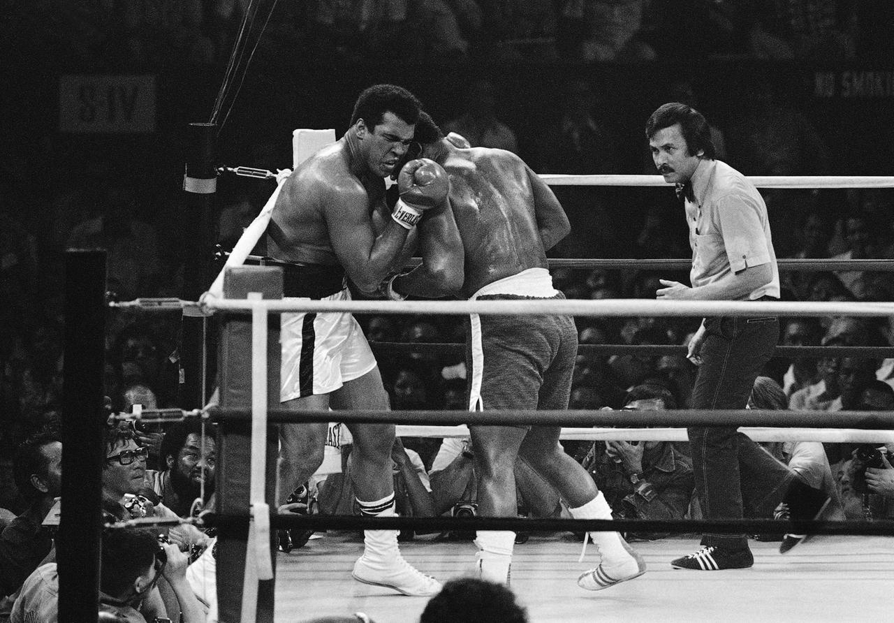 Muhammad Ali grimaces as he exchanges blows with Joe Frazier, at left, in first round of their title bout at the Araneta Coliseum in Manila, Philipppines, October 1, 1975. The referee is Carlos Padilla. (AP Photo)