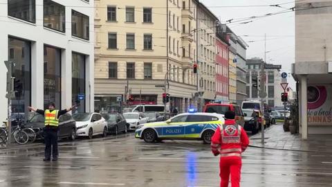 Ein Polizist steht in der Nähe des Einsatzortes und sperrt die Strape mit ausgebreiteten Armen.