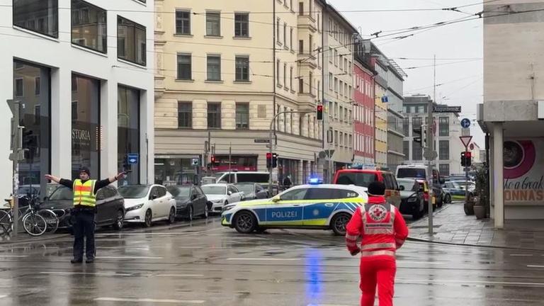 Ein Polizist steht in der Nähe des Einsatzortes und sperrt die Strape mit ausgebreiteten Armen. Ein Polizist steht in der Nähe des Einsatzortes und sperrt die Strape mit ausgebreiteten Armen.