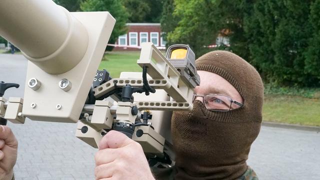 Ein Mensch mit Sturm-Haube schaut durch ein Stör-Geräte für Drohnen.