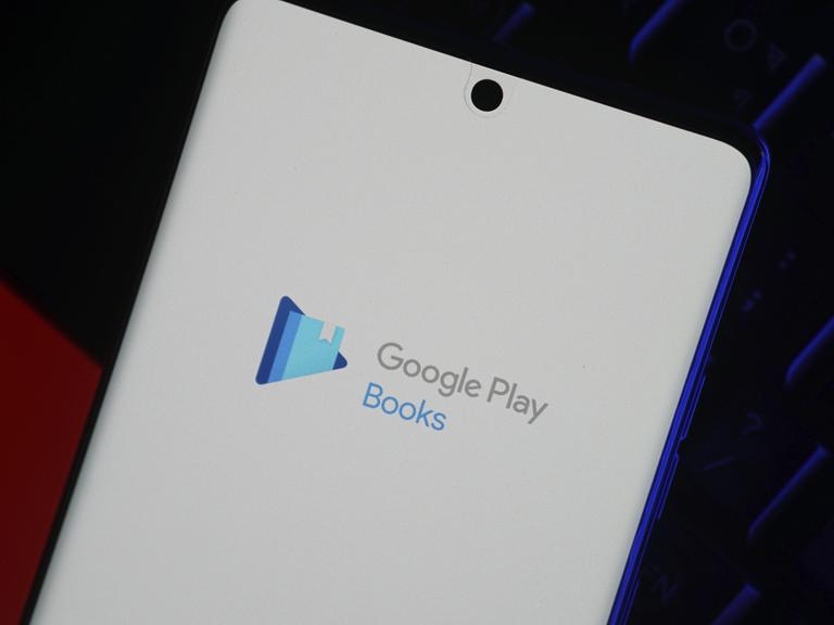 Smartphone mit dem Logo der Google Play Books App auf dem Bildschirm vor einem dunklen Hintergrund