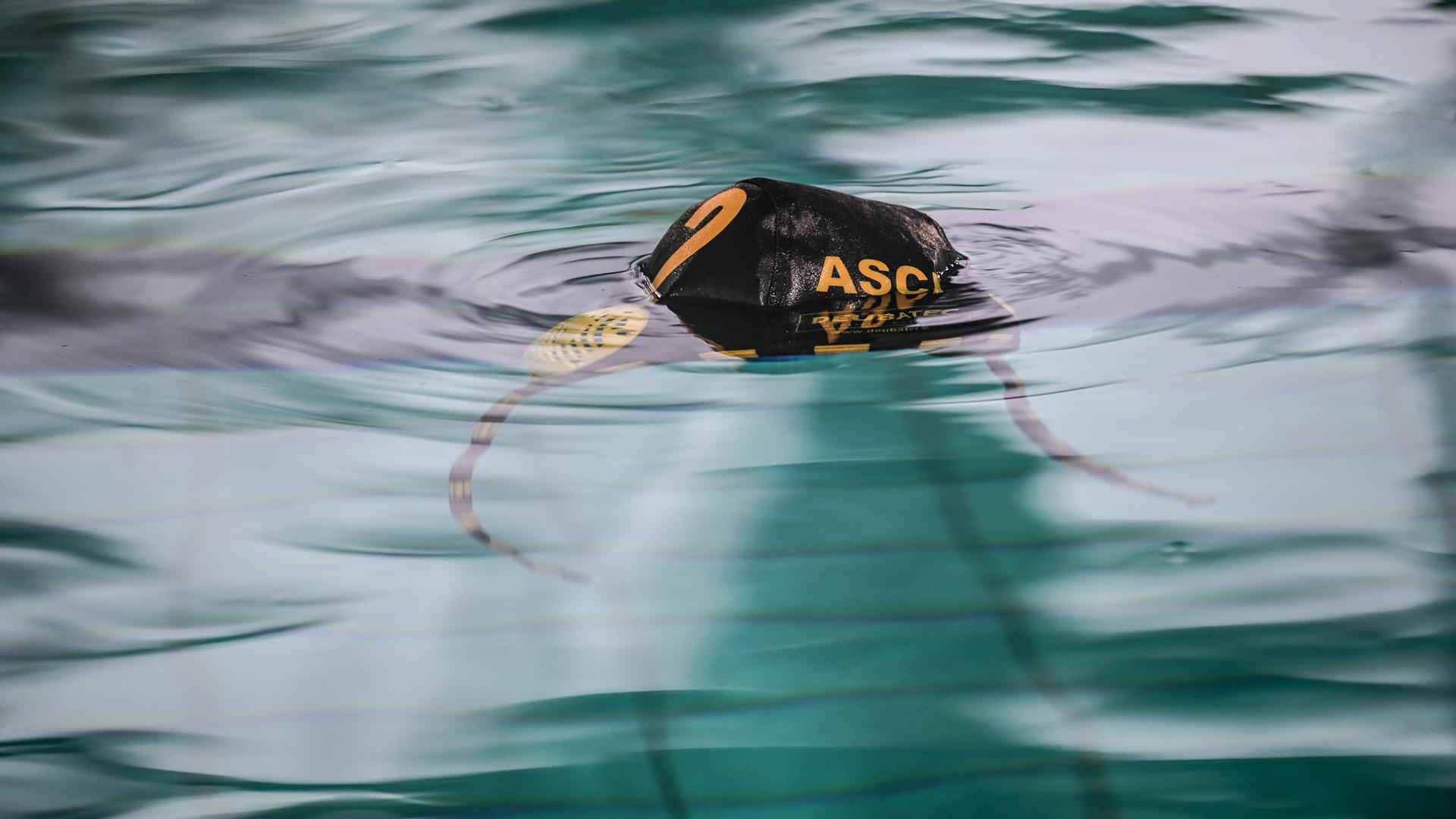 Eine Wasserball-Badekappe mit dem Schriftzug des ASC Duisburg schwimmt auf dem Wasser.