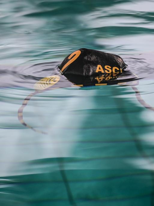 Eine Wasserball-Badekappe mit dem Schriftzug des ASC Duisburg schwimmt auf dem Wasser.