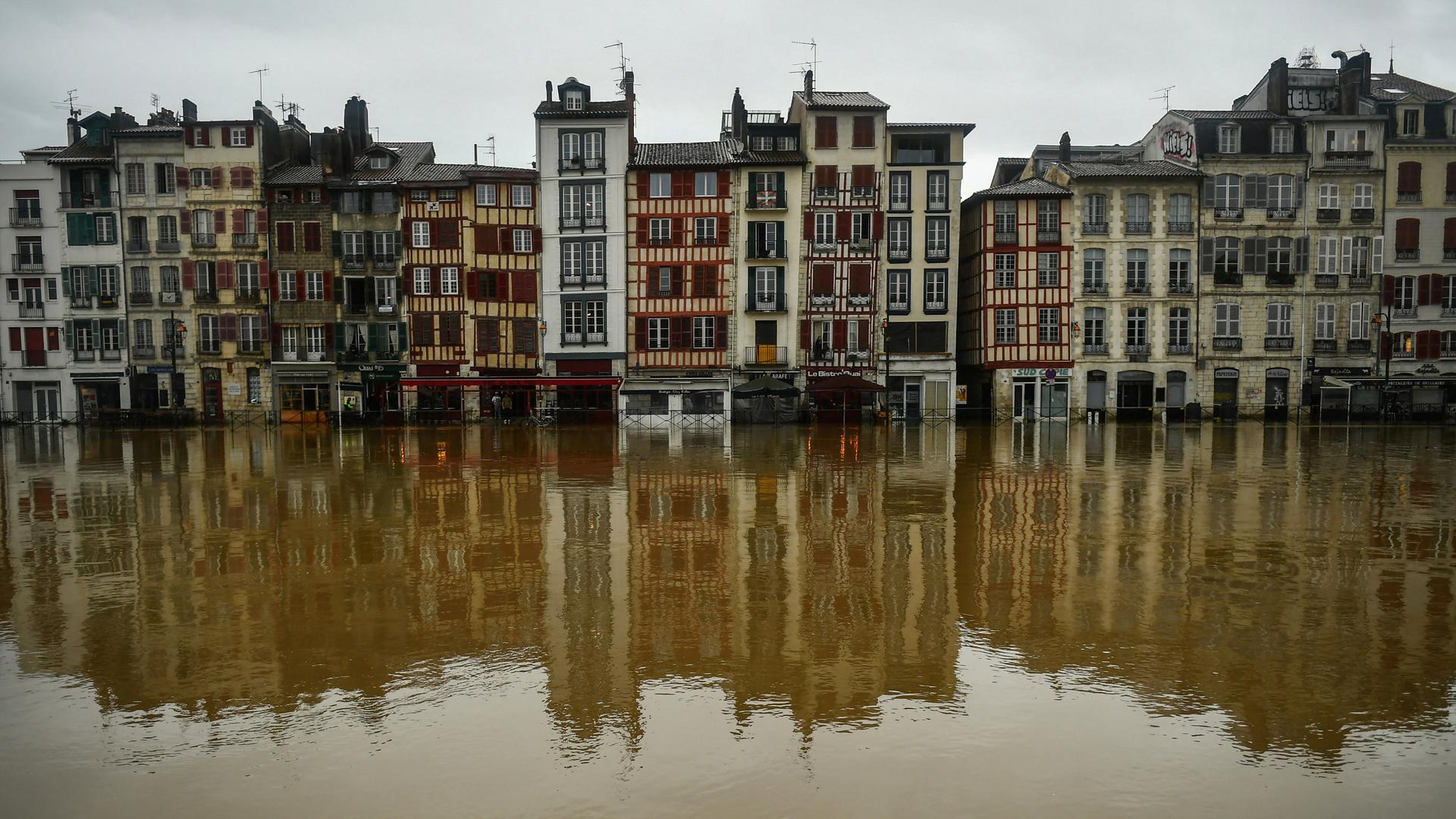 Eine Häuserfront steht infolge einer Überschwemmung im Wasser. Die Gebäude spiegeln sich auf der Wasseroberfläche.