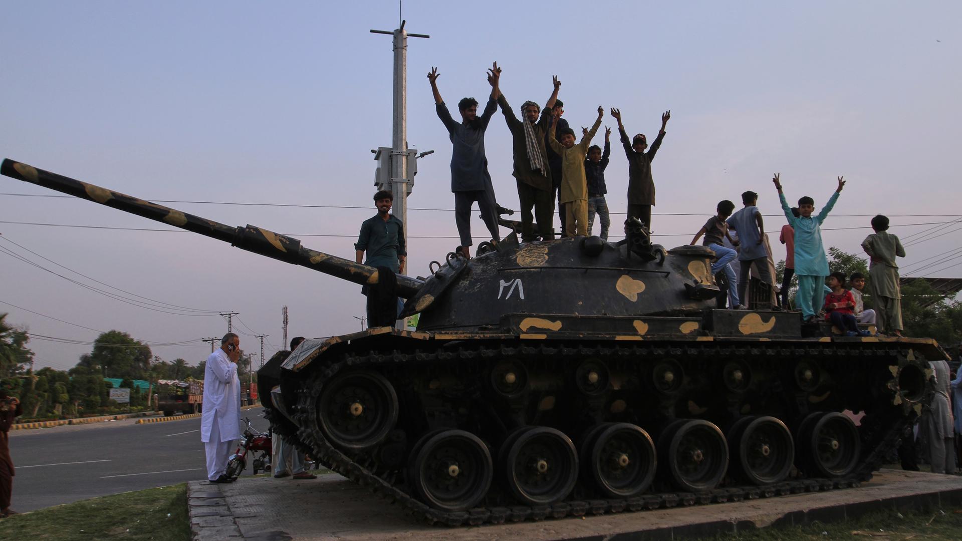 Während einer Demonstration zeigen Pakistaner Siegeszeichen und feiern auf dem Modell eines Panzers, nachdem Indien und Pakistan eine Waffenruhe vereinbart haben.
