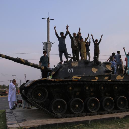 Während einer Demonstration zeigen Pakistaner Siegeszeichen und feiern auf dem Modell eines Panzers, nachdem Indien und Pakistan eine Waffenruhe vereinbart haben.