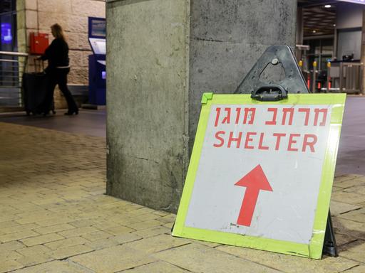 Vor dem leeren Eingang des Flughafens in Tel Aviv ist ein Hinweisschild zu sehen, auf dem "Shelter / Schutzraum" steht.