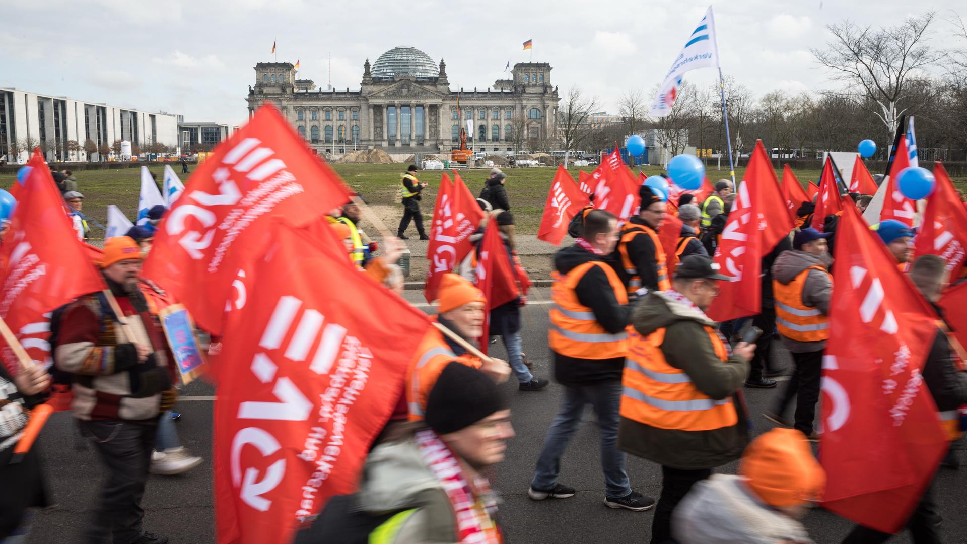 Teilnehmer der Demonstration gehen mit Flaggen und Warnwesten vor dem Reichstagsgebäude. Die Eisenbahn- und Verkehrsgewerkschaft (EVG) hatte zu einer Kundgebung vor dem Berliner Hauptbahnhof aufgerufen. 