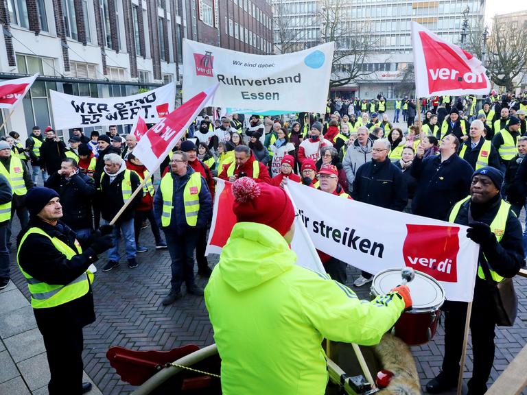 Mit Trommelschlägen und einem Transparent "Wir sind es wert" beteiligen sich Gewerkschaftsmitglieder an einer Streik-Kundgebung von Verdi.