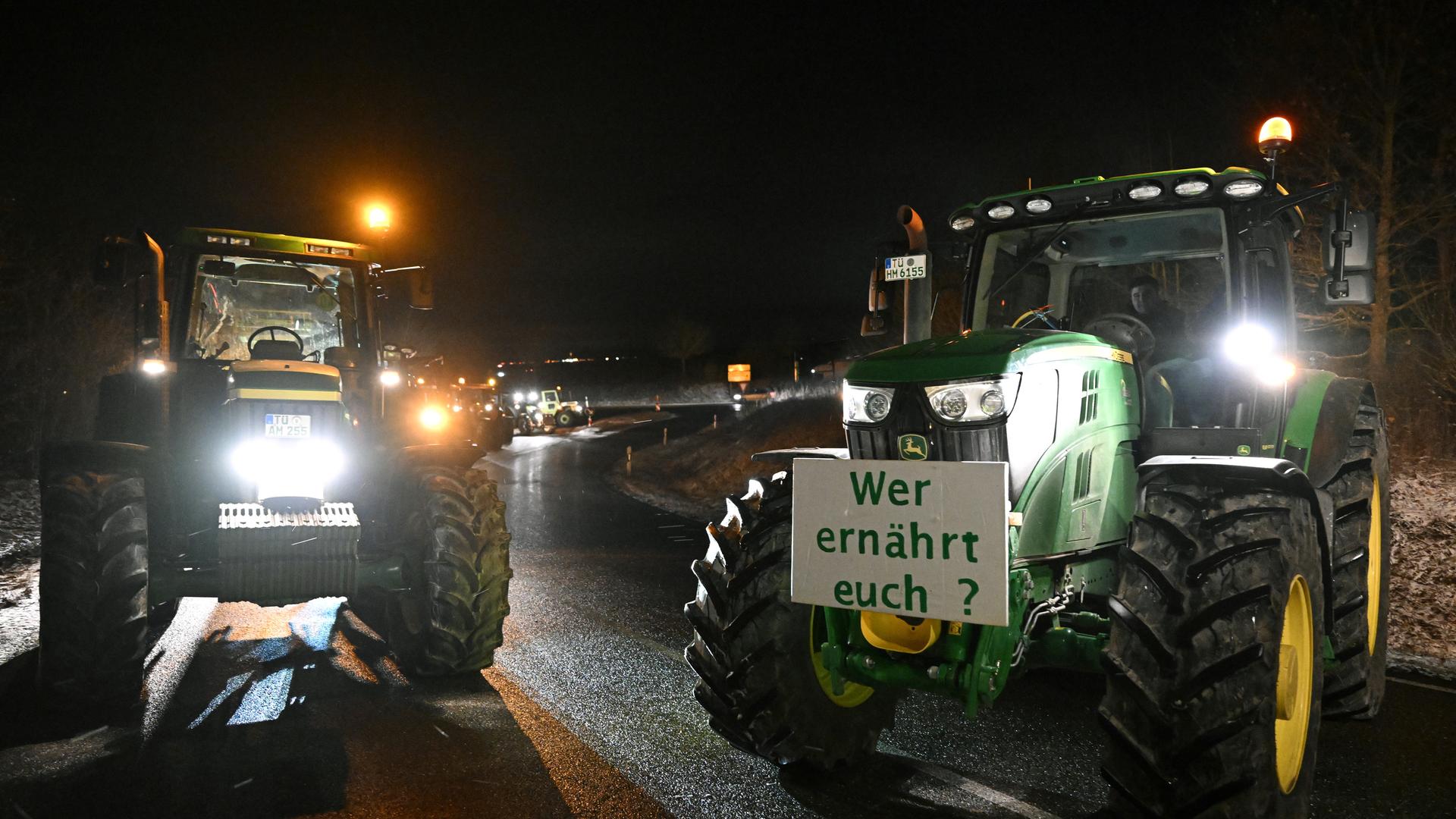 Bauernprotest an einer Autobahnauffahrt am 8. Januar 2024: Zwei Traktoren stehen mitten auf der Fahrbahn, an einem ist ein Schild befestigt mit der Aufschrift "Wer ernährt euch?" (Symbolbild)