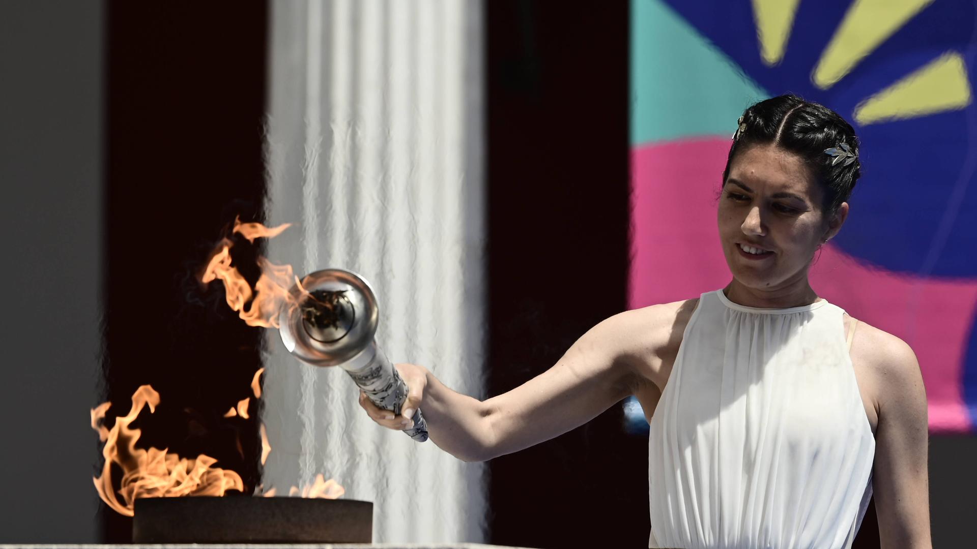 Eine Frau entzündet eine Fackel an einem Feuer. Man nennt das Feuer "Flamme der Hoffnung" für die Special Olympics.