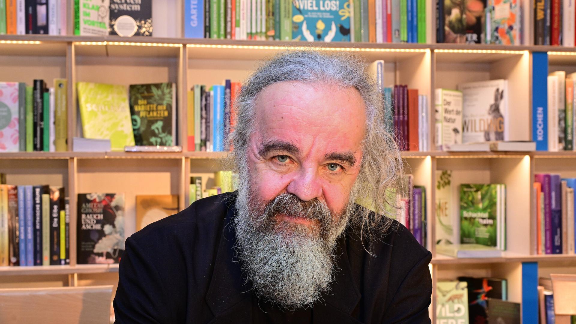 Der Schriftsteller Miljenko Jergović sitzt vor einem Bücherregal und schaut direkt in die Kamera.