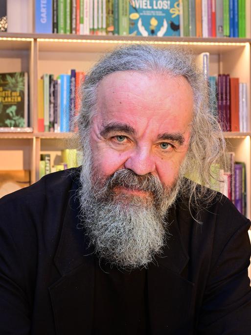 Der Schriftsteller Miljenko Jergović sitzt vor einem Bücherregal und schaut direkt in die Kamera.