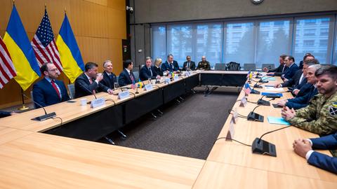 Vertreter der USA und der Ukraine sitzen sich an einem langen Tisch gegenüber. Sie  verhandeln über einen Friedens-Plan für die Ukraine. 