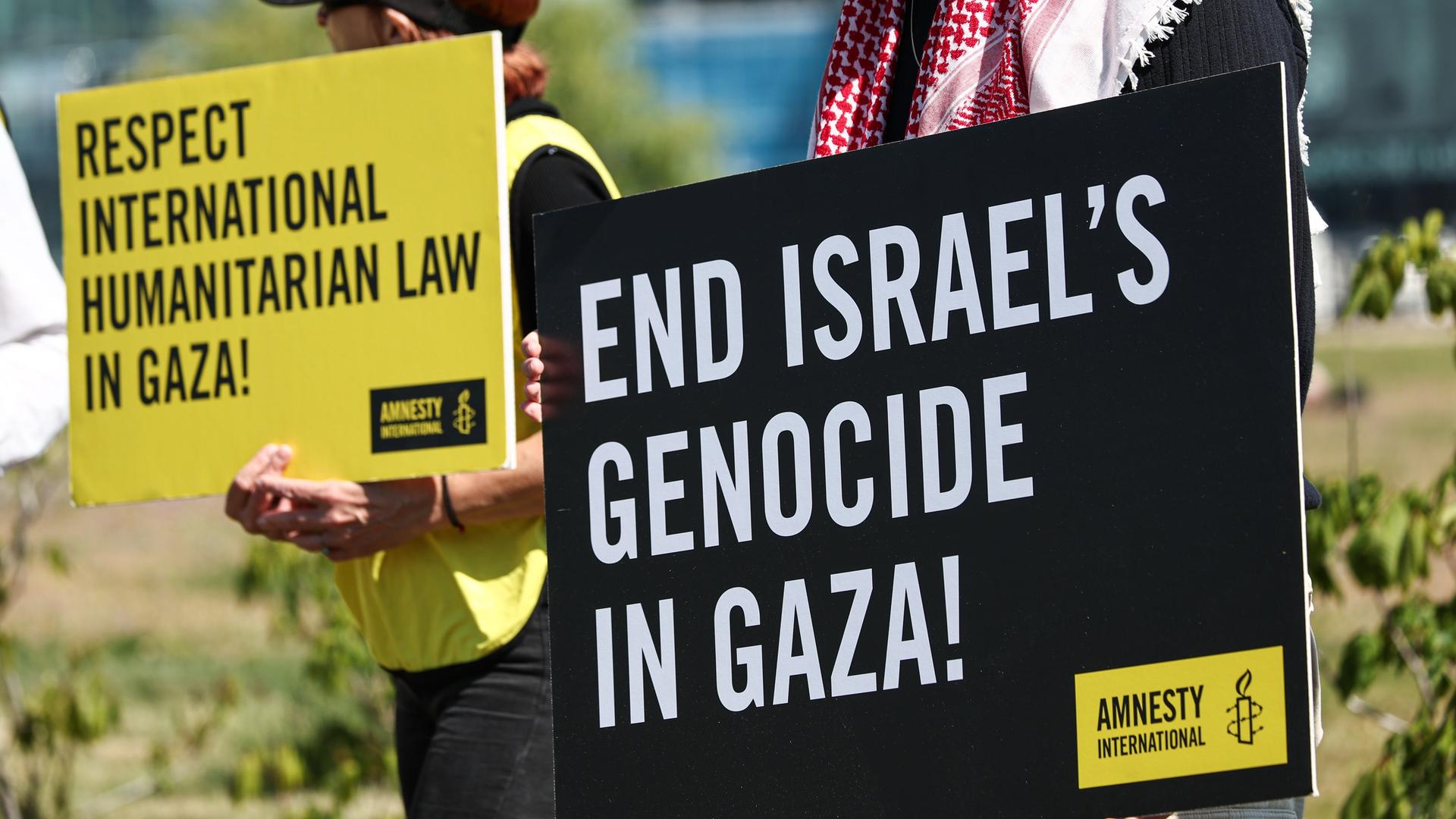 Teilnehmer einer Amnesty-International-Protestaktion gegen den Krieg im Gaza-Streifen halten Schilder vor dem Bundeskanzleramt.