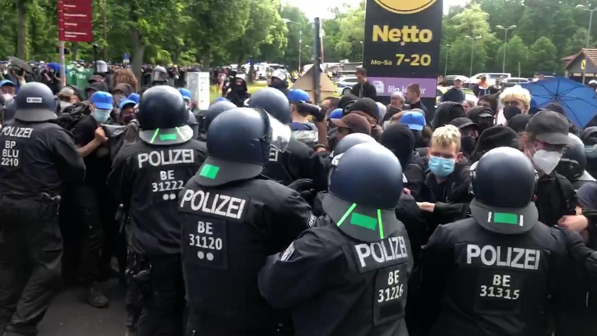 Polizeibeamte stehen bei einer Demonstration gegen Tesla neben den Demonstranten.