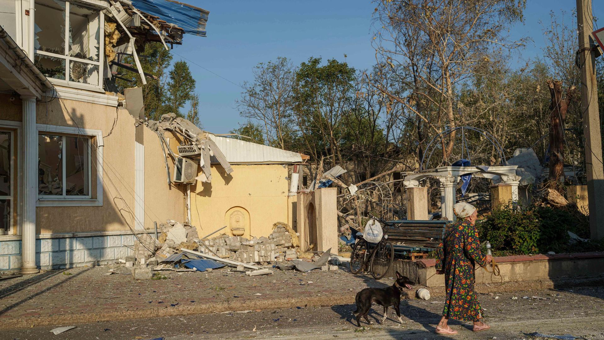 Eine Frau geht mit ihrem Hund vor einem Hotel in der ukrainischen Stadt Kramatorsk spazieren, das durch einen russischen Raketenangriff in Trümmern liegt.