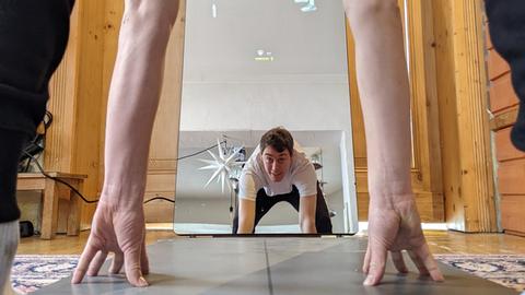 Ein Mann macht Fitness vor einem Fitness-Spiegel.
