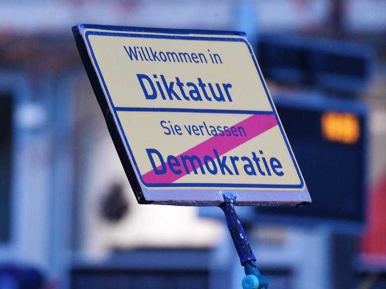 Auf einem Schild bei einer Demonstration der Querdenken-Bewegung steht "Willkommen in der Diktatur - Sie verlassen Demokratie".