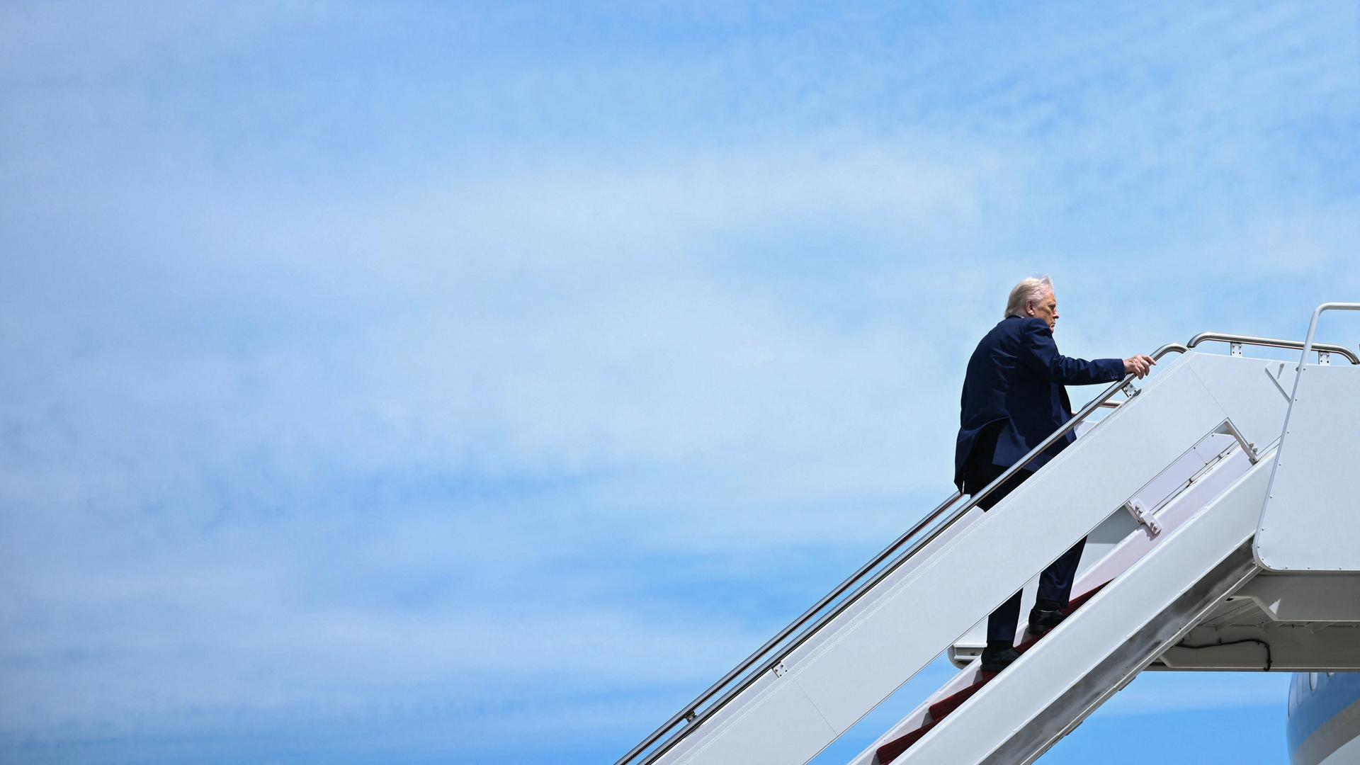 US-Präsident Donald Trump steigt die Gangway zur Airforce One hoch. Hinter ihm viel blauer Himmel. US-Präsident Donald Trump steigt die Gangway zur Airforce One hoch. Hinter ihm viel blauer Himmel.