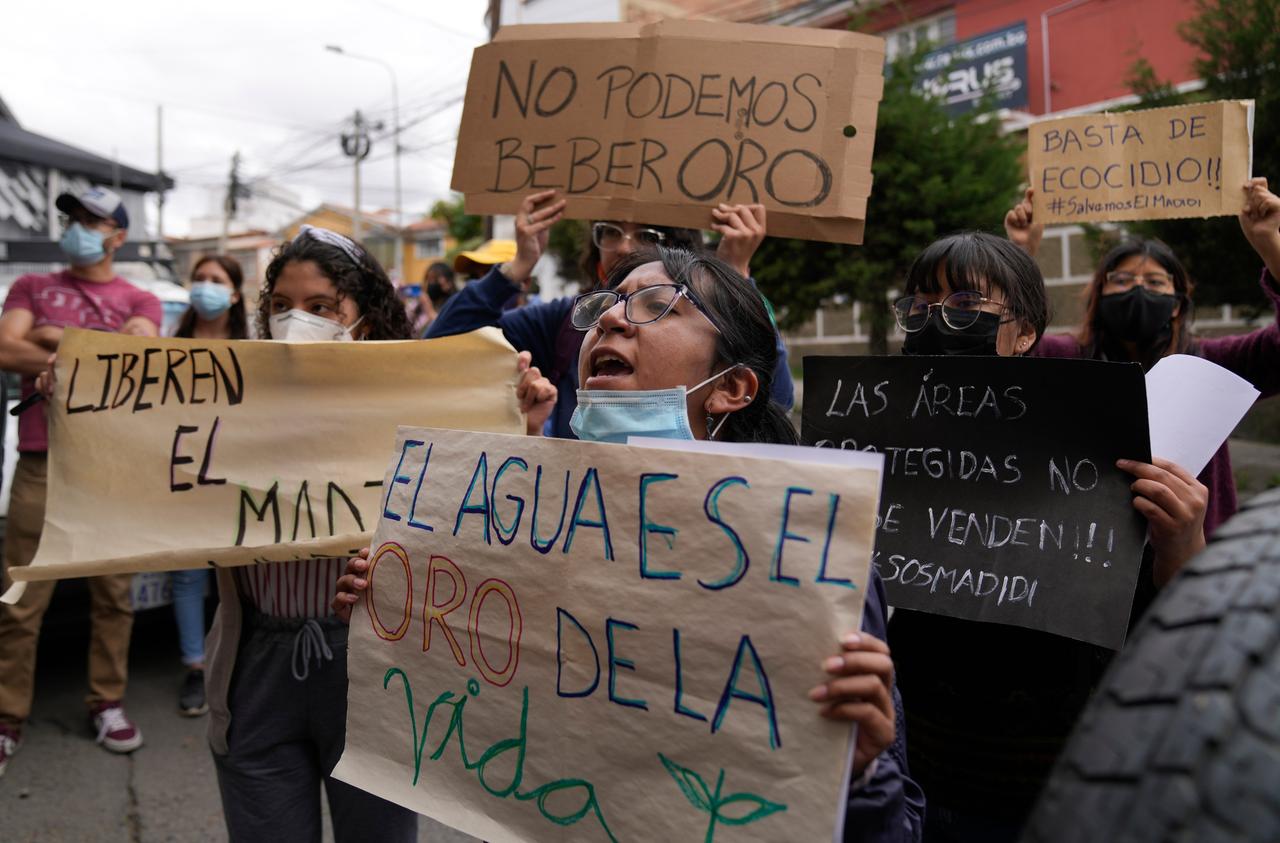 Menschen halten Plakate mit Aufschriften wie "Wir können Gold nicht trinken", "Wasser ist das Gold des Lebens", "Stoppt die Vernichtung der Umwelt". Sie protestieren vor der Nationalen Naturschutzbehörde in Boliviens Hauptstadt La Paz.