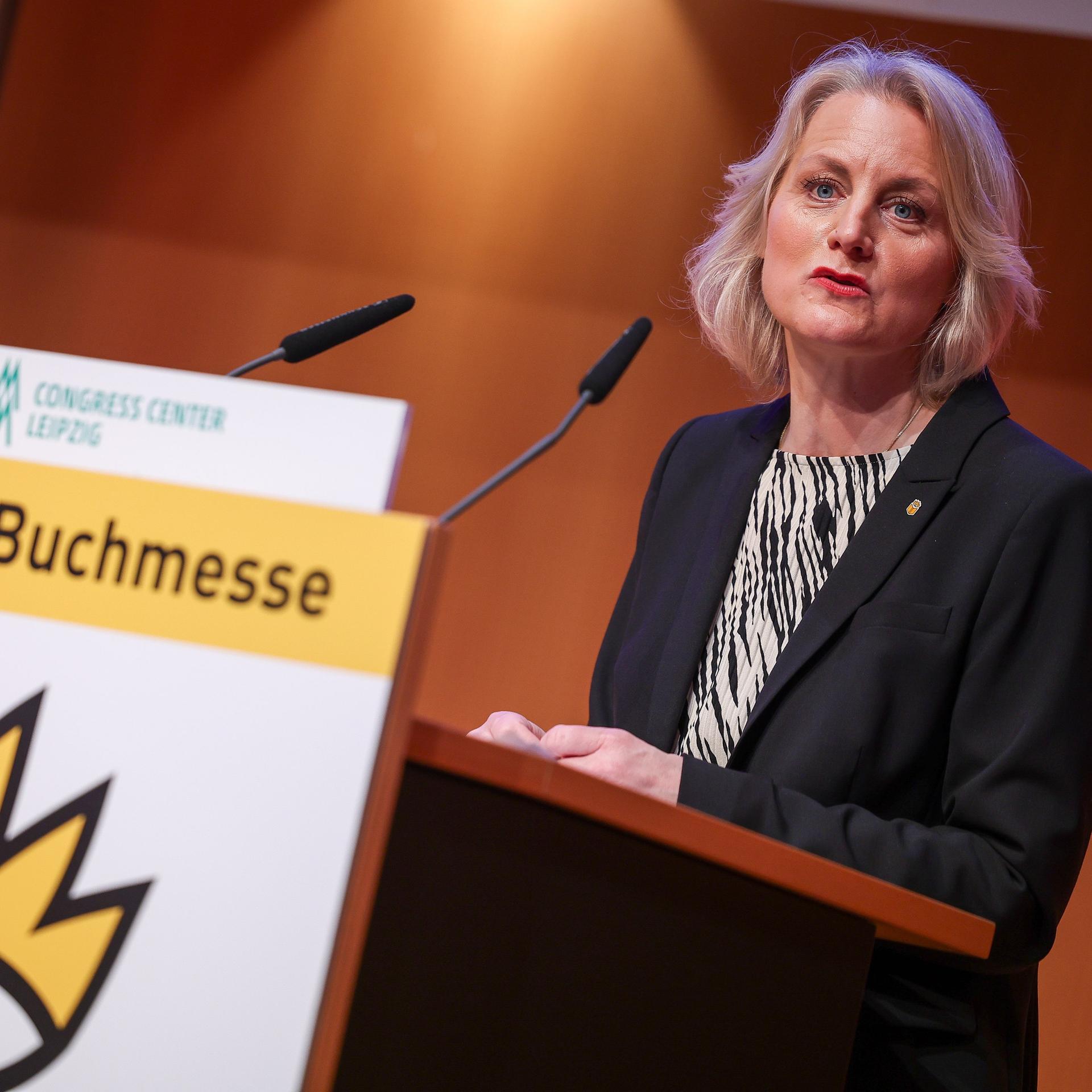 Astrid Böhmisch, Direktorin der Leipziger Buchmesse, spricht auf der Eröffnungs-Pressekonferenz der Leipziger Buchmesse. Sie steht an einem Pult mit dem Logo der Buchmesse und spricht in ein Mikrofon. 