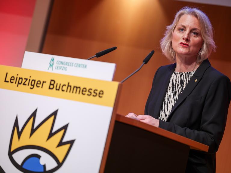 Astrid Böhmisch, Direktorin der Leipziger Buchmesse, spricht auf der Eröffnungs-Pressekonferenz der Leipziger Buchmesse. Sie steht an einem Pult mit dem Logo der Buchmesse und spricht in ein Mikrofon. 