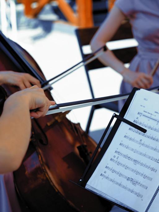Musiker und Musikerinnen spielen draußen Streichinstrumente