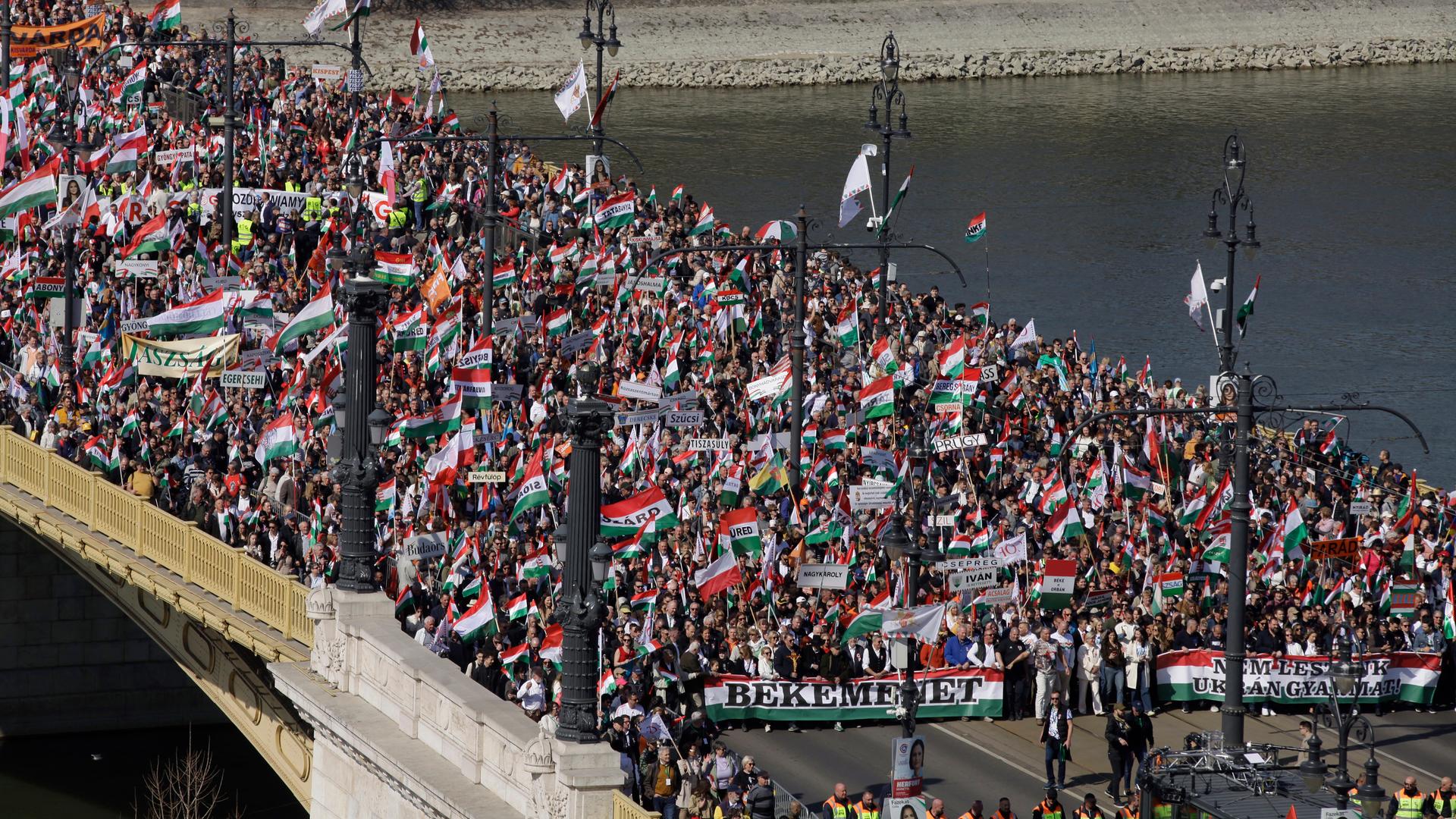 Tausende Menschen ziehen mit Fahnen und Bannern bei einem Demonstrationszug über eine Brücke in Ungarns Hauptstadt Budapest.
