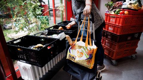 Eine Frau sammelt Obst aus einer Kiste in der Ausgabestelle Paul-Schneider-Haus der Berliner Tafel. 