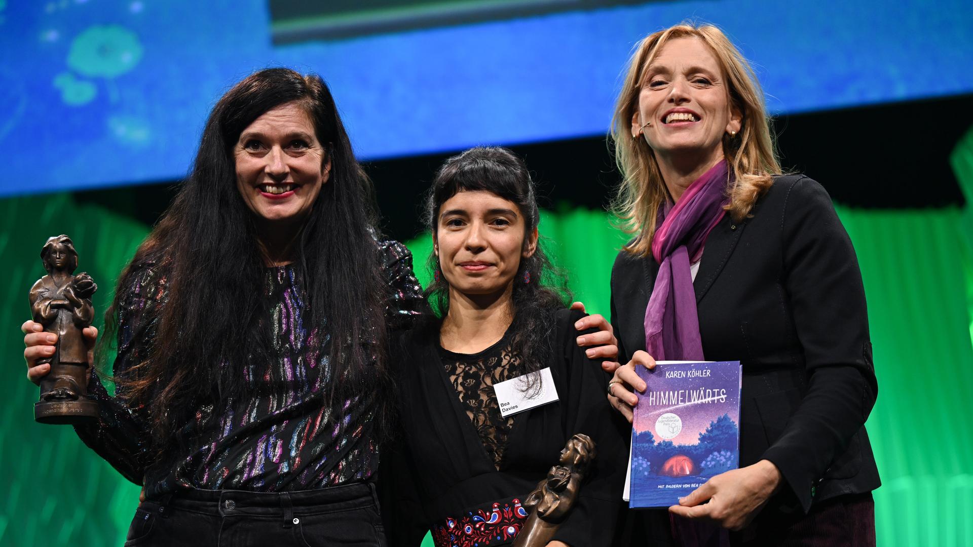 Die Autorin Karen Köhler (l) und die Illustratorin Bea Davies werden bei der Verleihung des Deutschen Jugendliteraturpreis 2025 auf der Frankfurter Buchmesse von Karin Prien mit der Momo-Trophäe ausgezeichnet. 