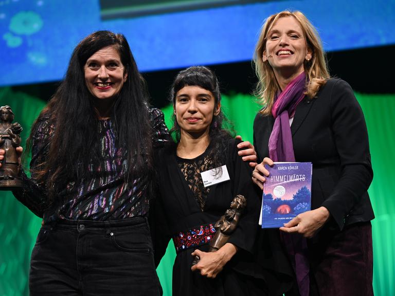 Die Autorin Karen Köhler (l) und die Illustratorin Bea Davies werden bei der Verleihung des Deutschen Jugendliteraturpreis 2025 auf der Frankfurter Buchmesse von Karin Prien mit der Momo-Trophäe ausgezeichnet. 
